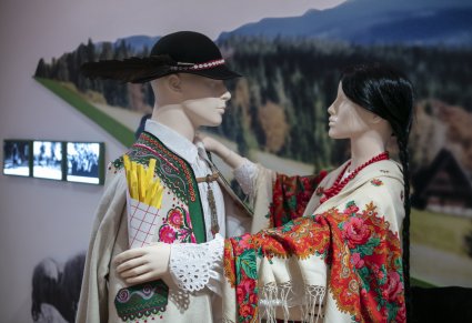 Para manekinów w kostiumach góralskich, dziewczyna trzyma w ręku paczkę frytek wykonanych z papieru