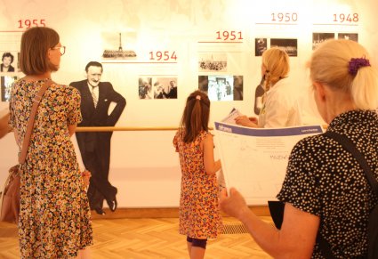 Sala ekspozycyjna, trzy dorosłe kobiety oraz jedna dziewczynka, zwiedzają, na ścianach wypisane daty, jedna z kobiet trzyma kartę z zadaniami