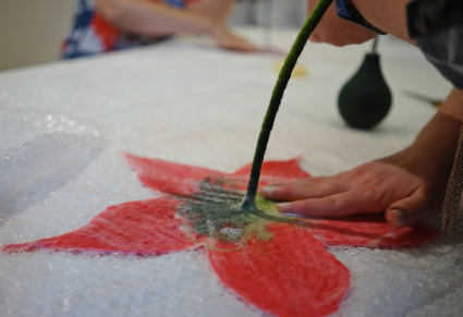 Uczestniczka warsztatów filcuje na mokro wełnianego kwiatka