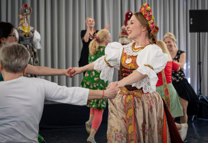 Uczestnicy warsztatów łącznie z osoba prowadzącą w kostiumie rozbarskim tańczą w kółkach na Sali Kameralnej Centrum Folkloru Polskiego "Karolin"