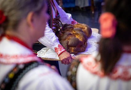 Tancerz Regionalnego Zespołu Podegrodzie trzyma na dużej tacy kukiełkę - pieczywo związane ze zwyczajem „wiązowin”.