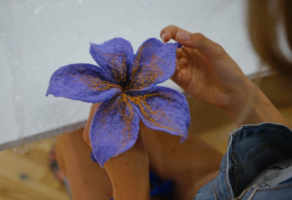 Uczestniczka warsztatów trzyma w ręku sfilcowanego kwiatka