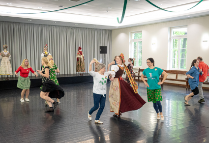 Uczestnicy warsztatu i osoba prowadząca w kostiumie rozbarskim tańczą trojaka na Sali Kameralnej Centrum Folkloru Polskiego "Karolin"