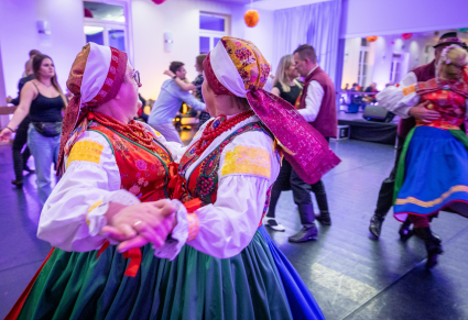 Uczestnicy potańcówki tańczą w parach na Sali Kameralnej Centrum Folkloru Polskiego "Karolin". Na pierwszym planie dwie tancerki Zespołu Regionalnego "Wilamowice" tańczące razem w parze