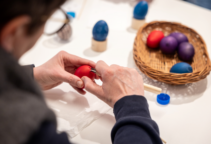 Uczestnik warsztatu wydrapuje wzór na jajku za pomocą ostrego narzędzia