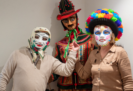 Uczestnicy warsztatu w samodzielnie wykonanych maskach pozują do zdjęcia przy manekinie ubranym w kostium śmiergustnika Zespołu "Mazowsze"