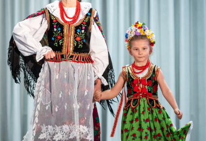 Uczestniczka "Pokazu Mazowszańskiej Mody" wraz z młodą dziewczynką na wybiegu, ubrane w kostiumy krakowskie