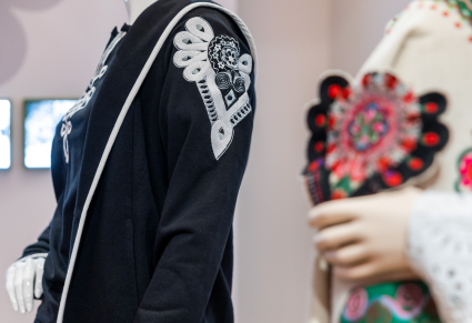 Manekin ubrany w kardigan z Kolekcji Mazowsze na wystawie Centrum Folkloru Polskiego "Karolin". Na ramieniu wyhaftowany wzór inspirowany parzenicą.  Kolejny manekin w ręku trzyma kolorową haftowaną parzenicę podhalańską