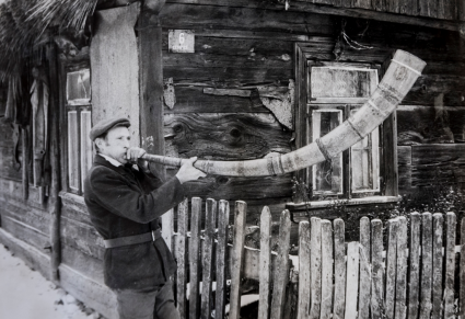 Mężczyzna stojący przy drewnianym płocie, grający na ligawce