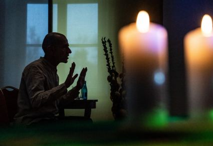 Na pierwszym planie dwie płonące świeczki. W tle Witold Vargas,  w profilu, siedzący na krześle, opowiadający