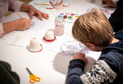 Uczestnicy warsztatów projektują wzór na dzwonki malując farbą na papierze