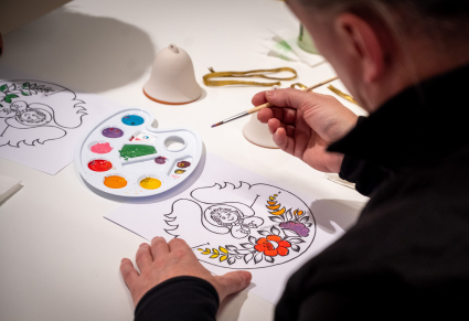 Uczestnik warsztatów projektuje wzór na dzwonki malując farbą na papierze