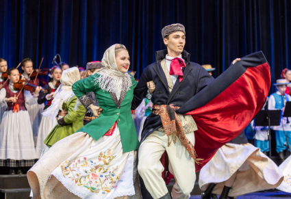 Tancerze Zespołu Tańca Ludowego "Leszczyniacy" ubrani w stroje biłgorajskich sitarzy tańczą w parze na głównej scenie