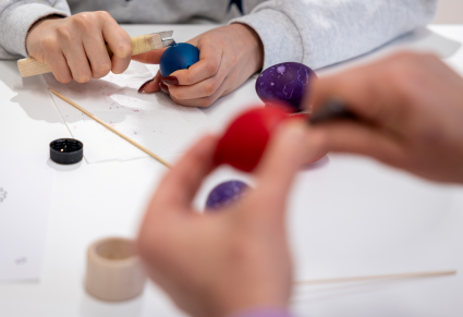 Uczestnicy warsztatu wydrapują wzory na jajku za pomocą ostrego narzędzia