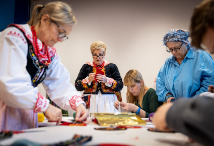 Kobiety w strojach regionalnych prowadzące warsztaty z haftu lachowskiego wraz z uczestnikami haftują podczas warsztatów w Sali Edukacyjnej Centrum Folkloru Polskiego 'Karolin"