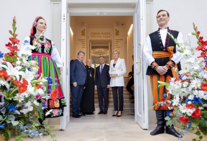 Para prezydencka, kardynał Kazimierz Nycz oraz dyrektor Zespołu Jacek Boniecki za szeroko otwartymi drzwiami Pałacu Karolin, przed drzwiami po lewej stoi  kobieta, po prawej mężczyzna, uśmiechnięci witają gości