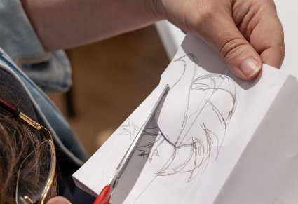Zbliżenie na dłonie dziewczynki, która wycina narysowanego na kartce koguta