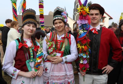 Młodzież w strojach kurpiowskich pozują do zdjęcia z palemkami