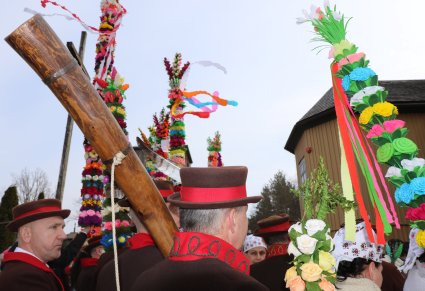Osoby w strojach z kurpiowskich z ligawką i palmami przed kościołem pod wezwaniem Św. Anny w Łysych