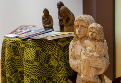 Drewniane rzeźby, tkanina dwuosnowowa zielona oraz książki wystawione na stolikach