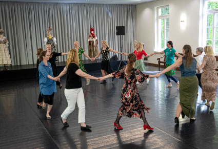 Uczestnicy warsztatu tańczą w kole na Sali Kameralnej Centrum Folkloru Polskiego "Karolin", trzymając się za ręce