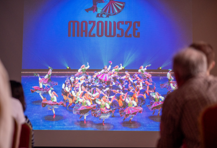 Zdjęcie Zespołu Mazowsze w "finale" do spektaklu "Kalejdoskop Barw Polski" wyświetlone jako część prezentacji towarzyszącej spotkaniu