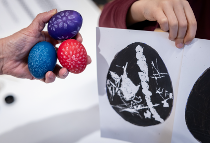 Uczestnicy warsztatu pokazują swoje prace: trzy jajka wykonane techniką rytowniczą i wydrapany wzór na malowanym na papierze jajku
