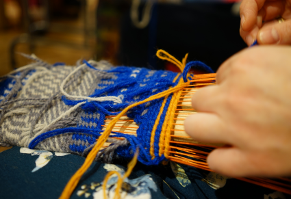 Uczestniczka warsztatów podczas tkania rękawicy na formie do tkania
