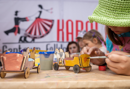 Uczestnicy warsztatów malują zabawki drewniane w namiocie warsztatowym Centrum Folkloru Polskiego "Karolin"
