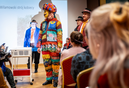 Mężczyzna przebrany za wilamowskiego śmierguśnika prezentuje strój podczas prelekcji w Centrum Folkloru Polskiego "Karolin".