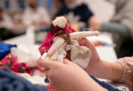Dziecięce ręce trzymają niedokończoną materiałową lalkę.