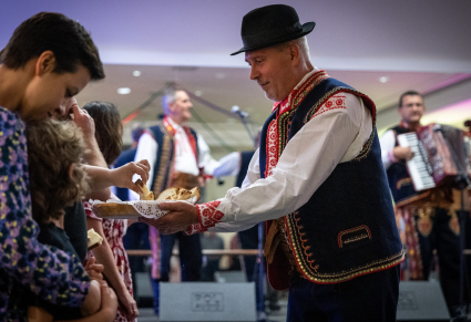 Członek Zespołu Regionalnego "Podegrodzie" częstuje gości kukiełką – pieczywem związanym ze zwyczajem „wiązowin”