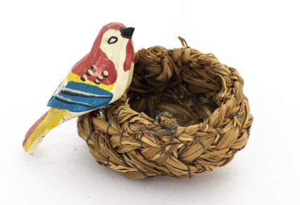 Drewniana figurka kolorowego ptaka, umieszczony jest na wiklinowym, plecionym gnieździe