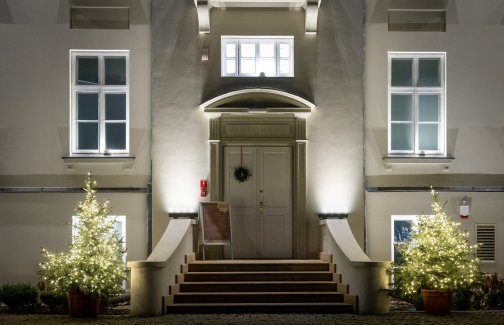 Karolin Palace at night. Shot of the front door, external staircase and ground floor windows nearest the main entrance. The staircase is lit up
