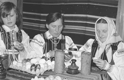 Kobiety i dziewczynka z okolic Opoczna w strojach ludowych zdobiące pisanki woskiem