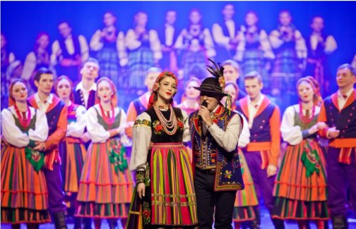 Zdjęcie z koncertu Mazowsze i De Mono, wokalista zespołu w towarzystwie kobiety w kostiumie łowickim