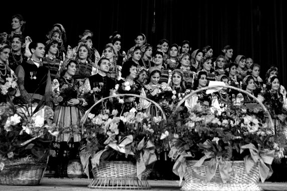 Zadęcie archiwalne przedstawiające artystów zespołu Mazowsze, pośrodku stoi Mira Zimińska-Sygietyńska, z przodu kosze kwiatów