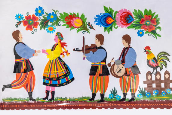 Łowicka, kolorowa wycinanka z papieru, na niej po lewej stronie tańcząca para,  po prawej dwóch muzyków grają na skrzypcach i bębnie, obok nich kolorowy kogut na siedzi płocie