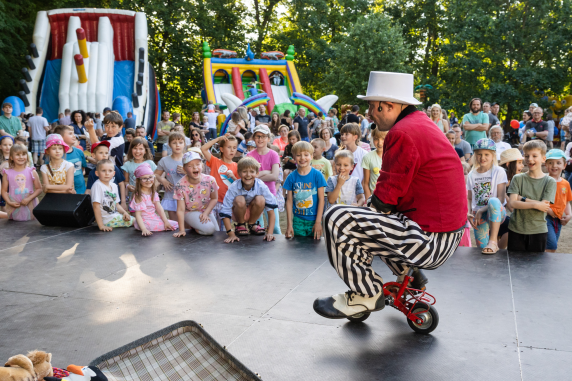 Grupa dzieci przed sceną, na której odbywa się pokaz cyrkowy