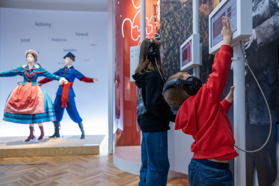 Dwójka dzieci zwiedzająca wystawę, stojąca przy stanowiskach multimedialnych