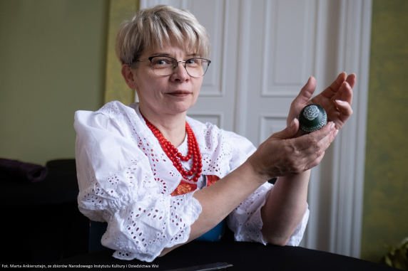 Ms Sabina Karwat holding a "kroszonka" - a dyed egg decorated suing the scratching technique