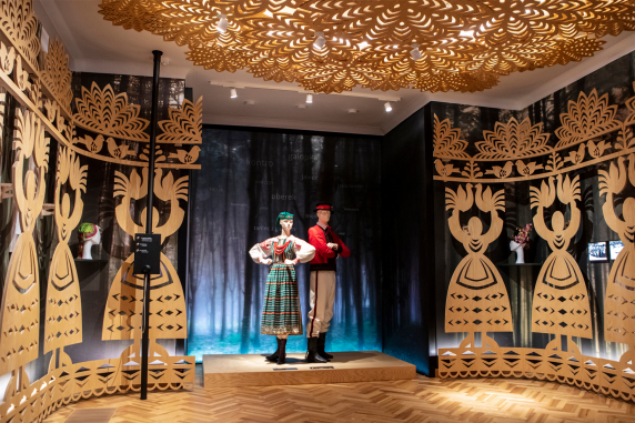 The exhibition at the palace. Visible are costumes inspired by traditional dress from the Kurpie region. The wooden decorations represent paper cut outs from the Kołbiel region