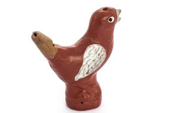 A ceramic whistle in the shape of a bird, painted red with a white wing