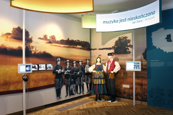 The exhibition at the palace. Visible are folk costumes based on traditional dress from the Opoczno region. The quotation on the panels reads: “Music is never ending” Jan Gaca/ fiddler
