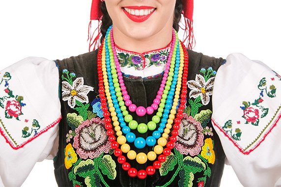 Part of a woman’s head - her nose, smiling lips - and upper body, dressed in costume from the Łowicz region